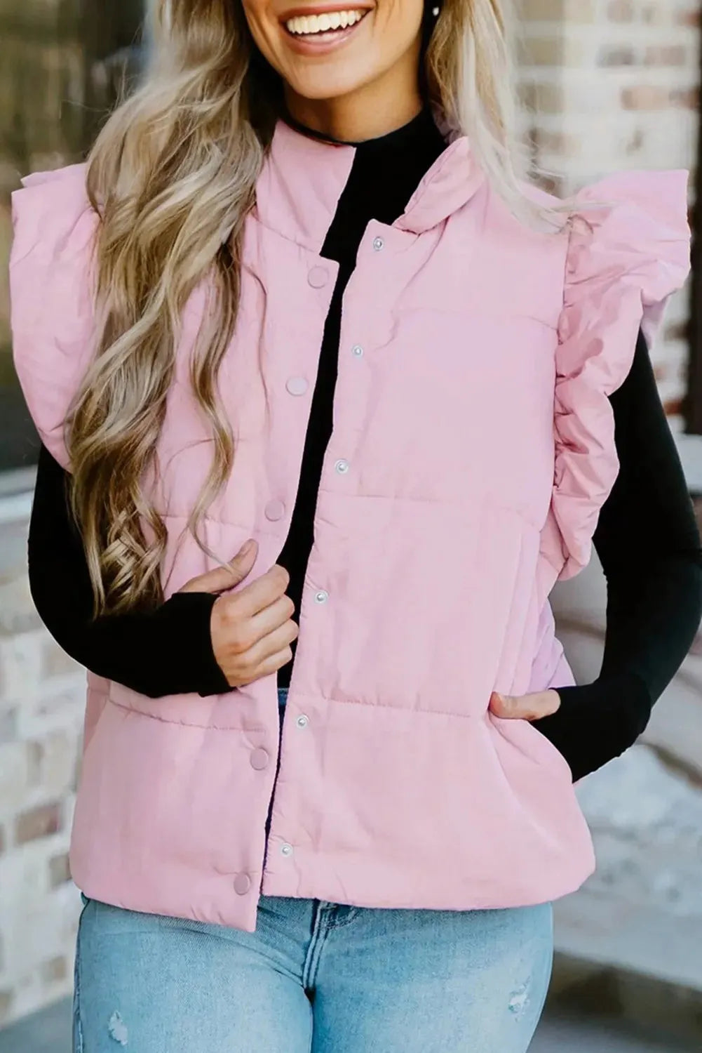 Pink stand neck puffer vest with flutter sleeves and snap buttons on a plain background