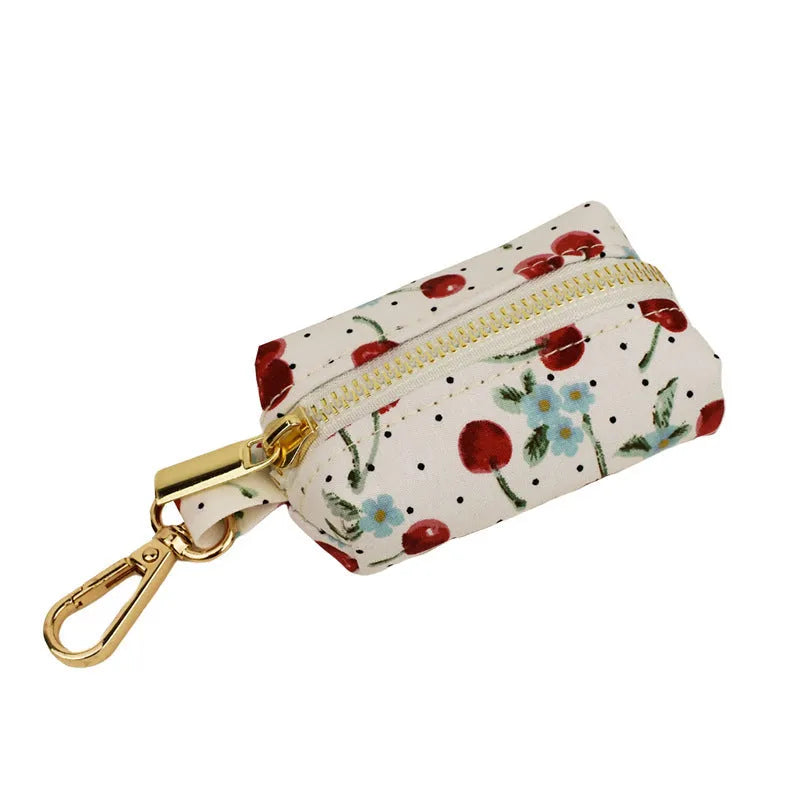 Red cherry print dog collar and leash set with light gold buckle, matching vest, bow, and poop bag holder.