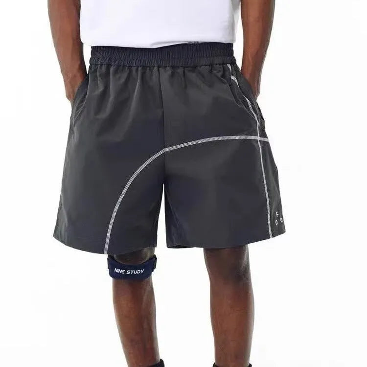 Man wearing retro-style light-coloured drawstring shorts with a loose fit, on a beach.