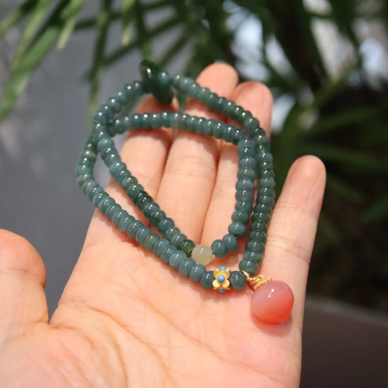 Blue water abacus and jade bead bracelet with tourmaline rings and pearl accents on a wrist.
