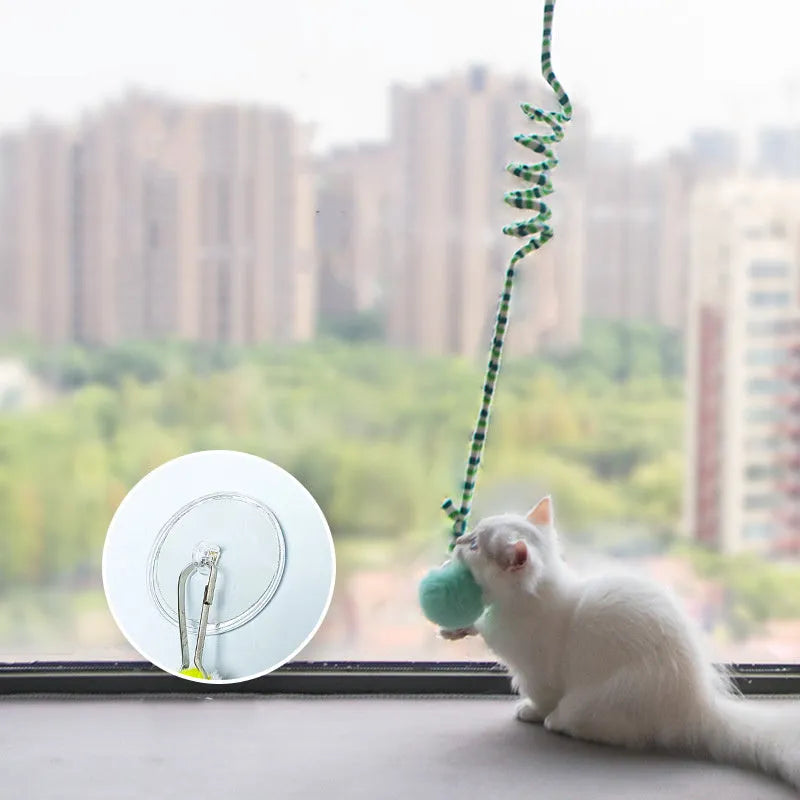 Colourful spring-mounted cat toy with an inflatable ball and bell, shown with a suction cup for hanging.