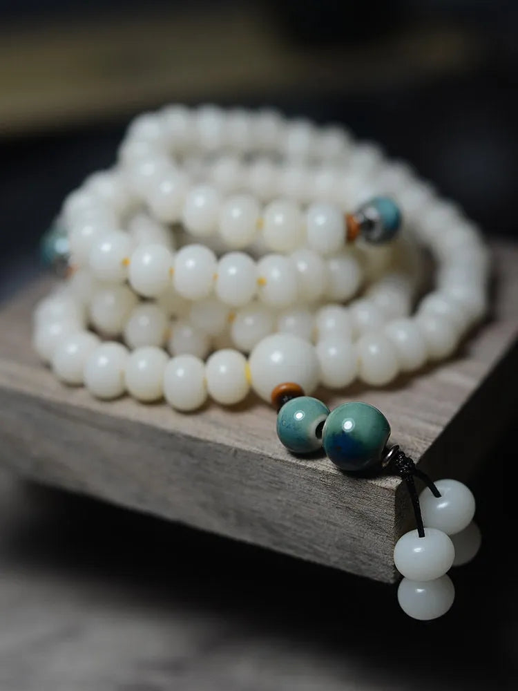 White jade bodhi root bracelet with 108 flat round beads in two sizes on wrist