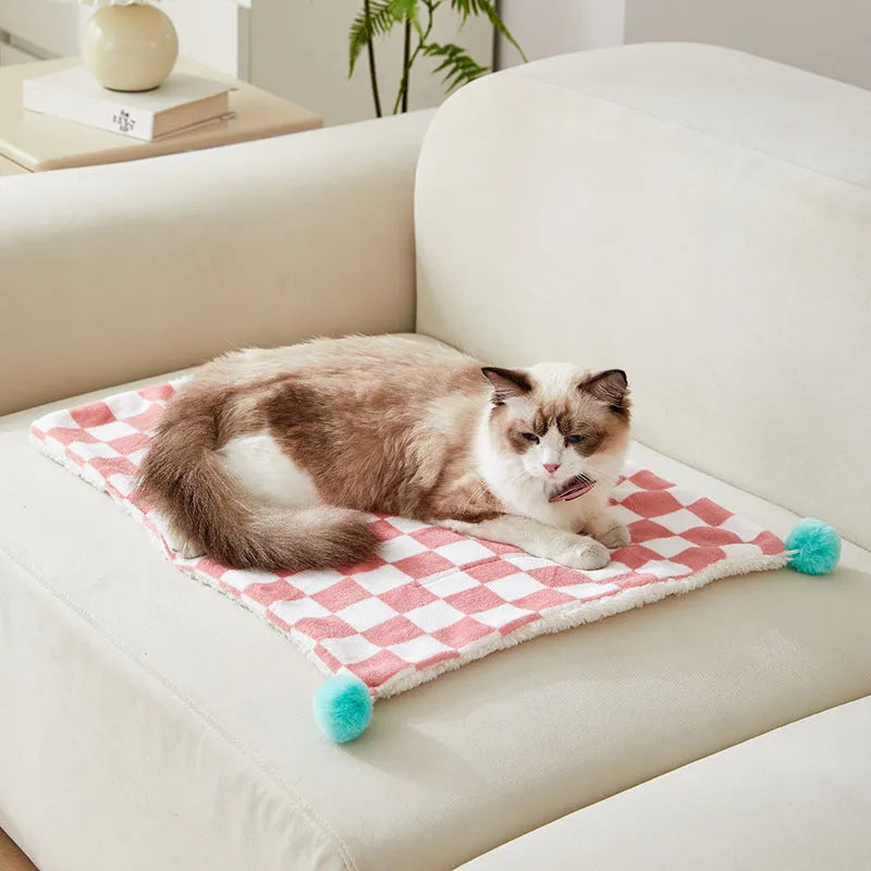 Soft plaid pattern pet blanket with fur ball decoration on a sofa