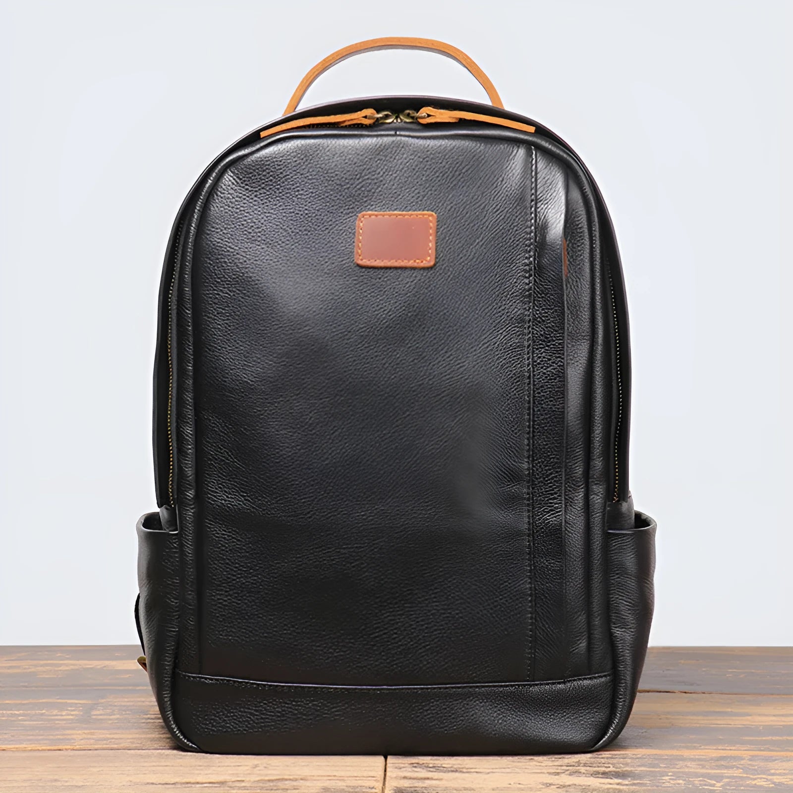 Black genuine leather expandable backpack with top grain cowhide, curved shoulder straps, and patchwork detail