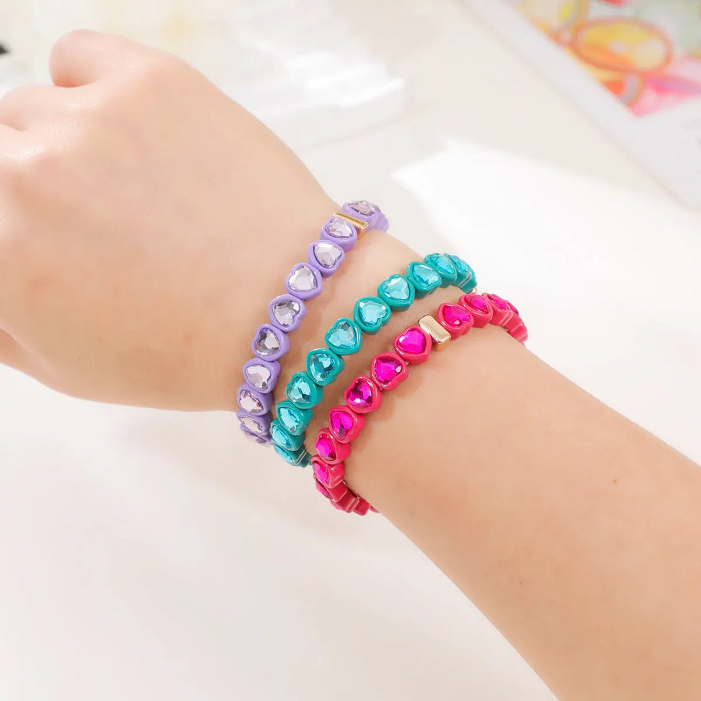 Colourful rainbow enamel heart-shaped stretch bracelet on a wrist.