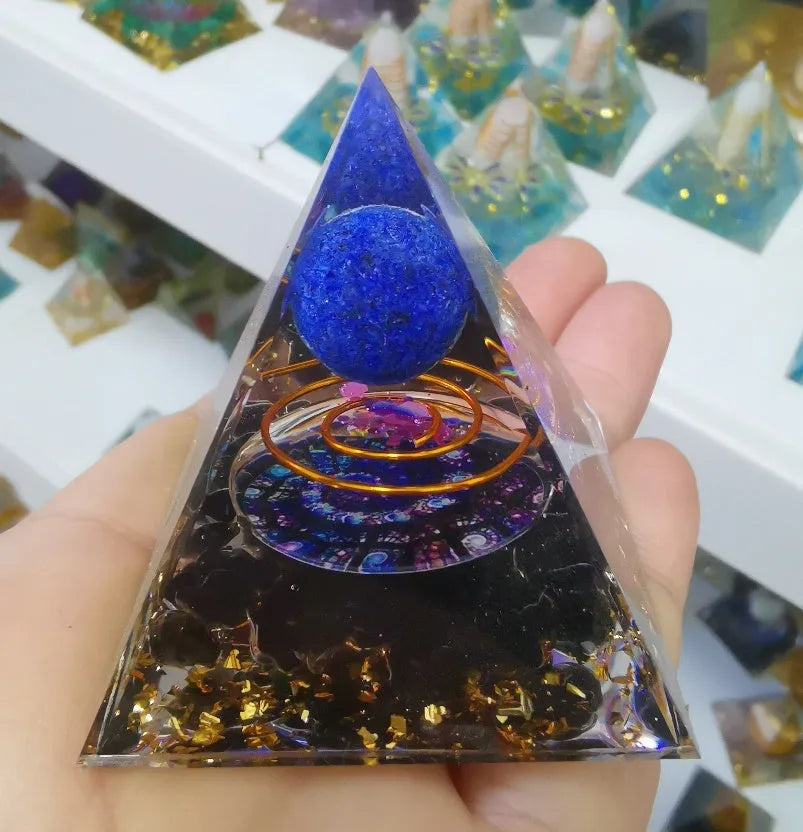 Clear epoxy resin pyramid ornament with natural crystal gravel inside on a wooden surface.