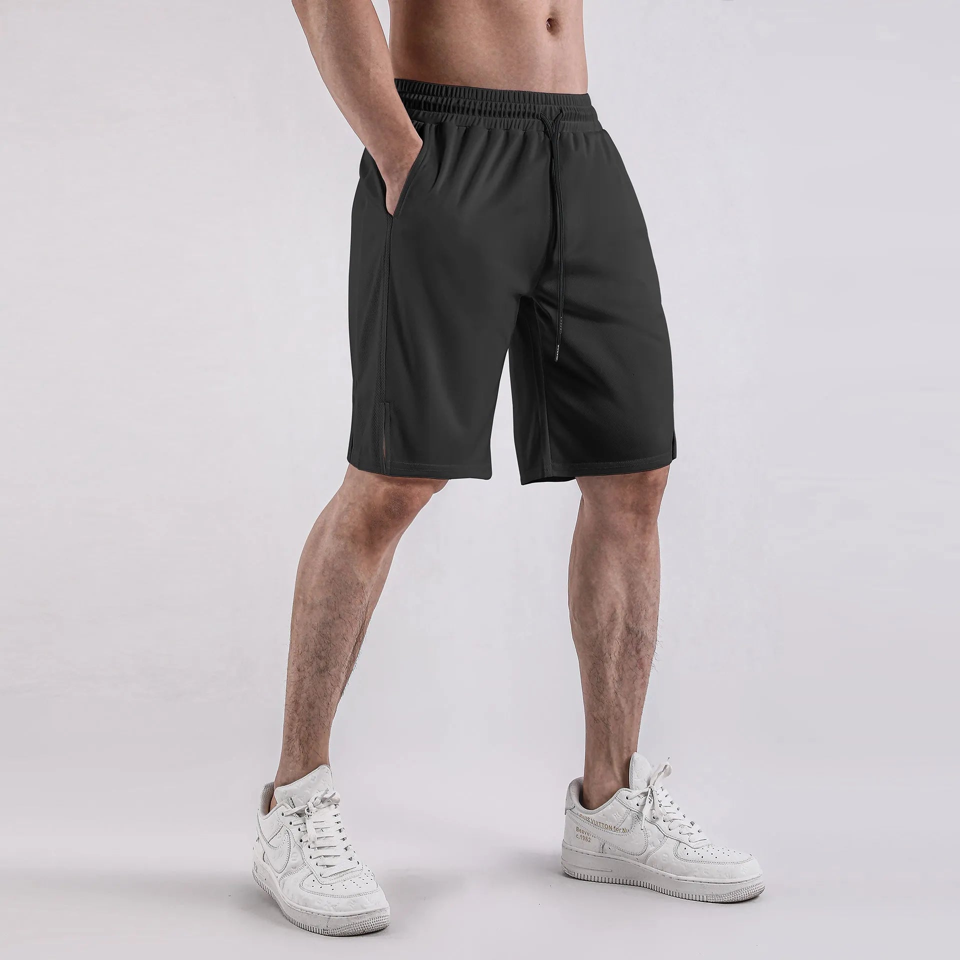 A man wearing loose-fitting black quick-dry mesh fitness shorts with an elastic waist.