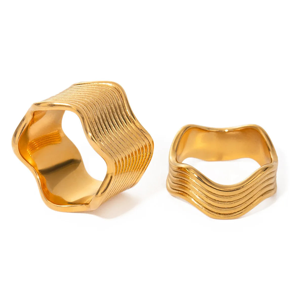 Silver and gold-tone stainless steel ring with a wide geometric wave design on a flat surface.