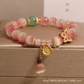 Close-up of a women's bracelet with a pink opal butterfly charm on an electroplated chain.