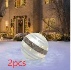 Large red and white striped inflatable Christmas ball ornament hanging on an outdoor tree