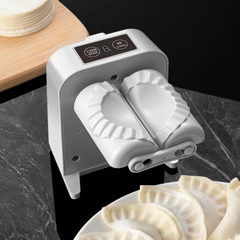 White automatic electric dumpling maker machine with charging cable, brush, and spoon.