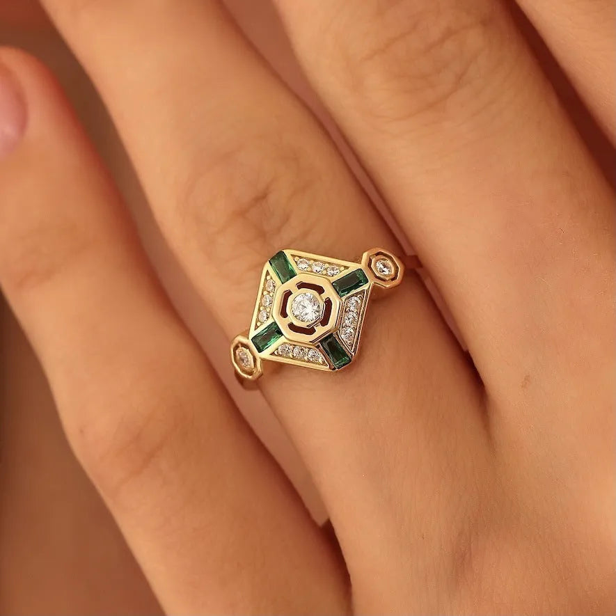 Square-shaped gold tone ring with emerald diamond colour on a model finger.