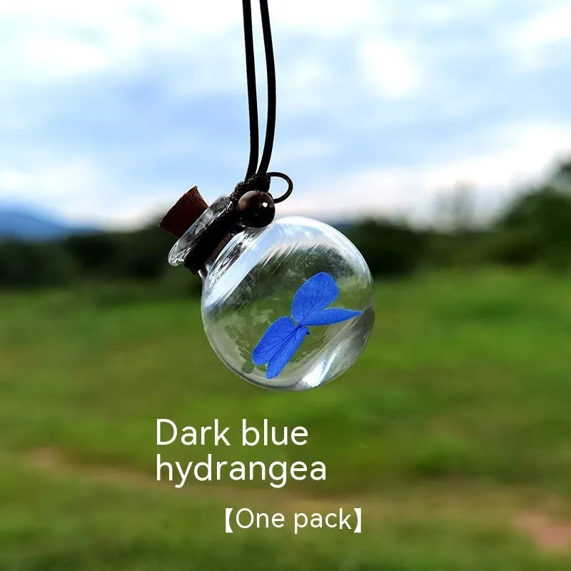 Glass car perfume pendant with preserved flower decoration hanging in car interior