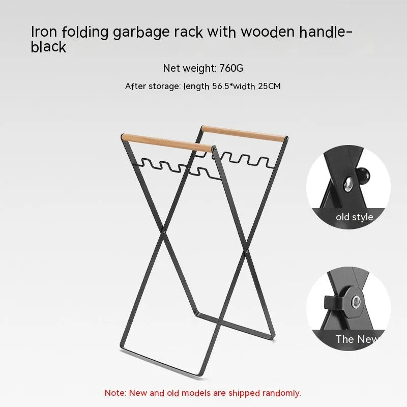 Black iron folding trash storage rack with a wooden handle for hanging bin bags.