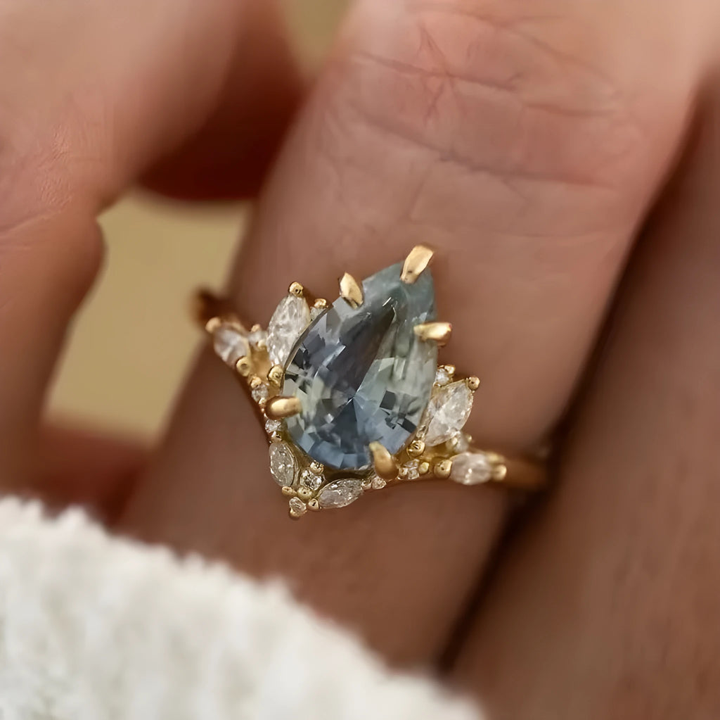 Gold alloy floral ring with aquamarine crystal centre on white background
