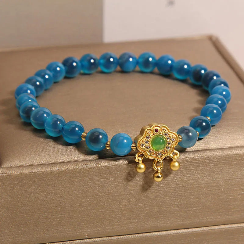 Blue sugar heart agate safety lock pendant on a women's crystal bracelet with rhinestone details.