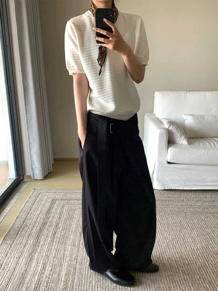 Black single pleated straight-leg trousers with an adjustable waistband on a hanger.