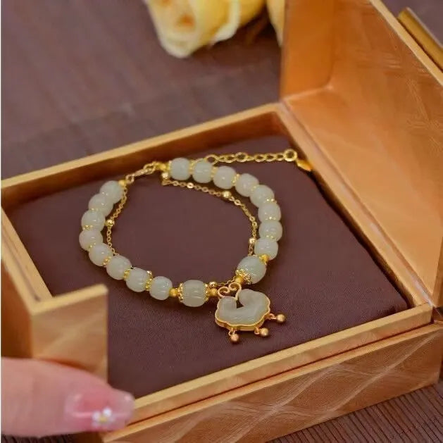 Close-up of a women's green double-layer bracelet with a drop-shaped Xiangyun safety lock pendant.
