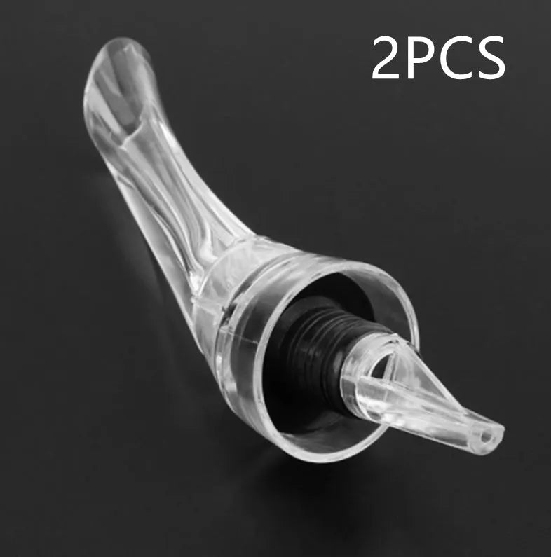 A clear acrylic wine aerator with a stainless steel filter, shown next to a wine glass.