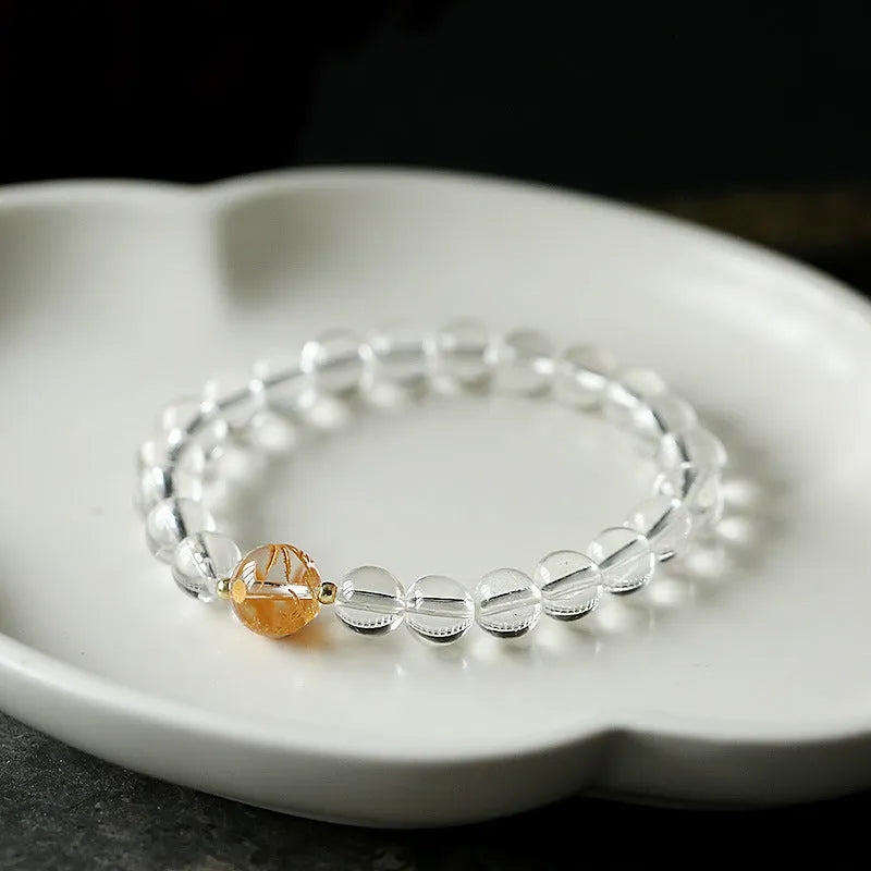 Geometric obsidian and white crystal bracelet with a golden dragon focal bead on a wrist.