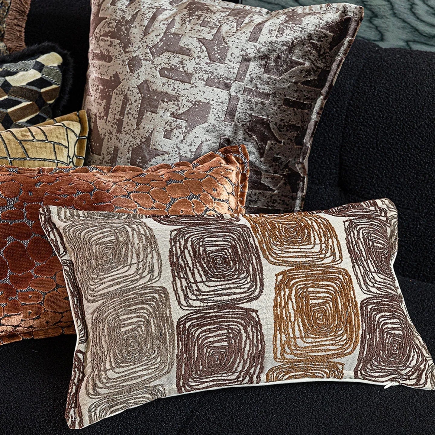 Square cream and coffee abstract coil pattern cushion cover on a grey sofa