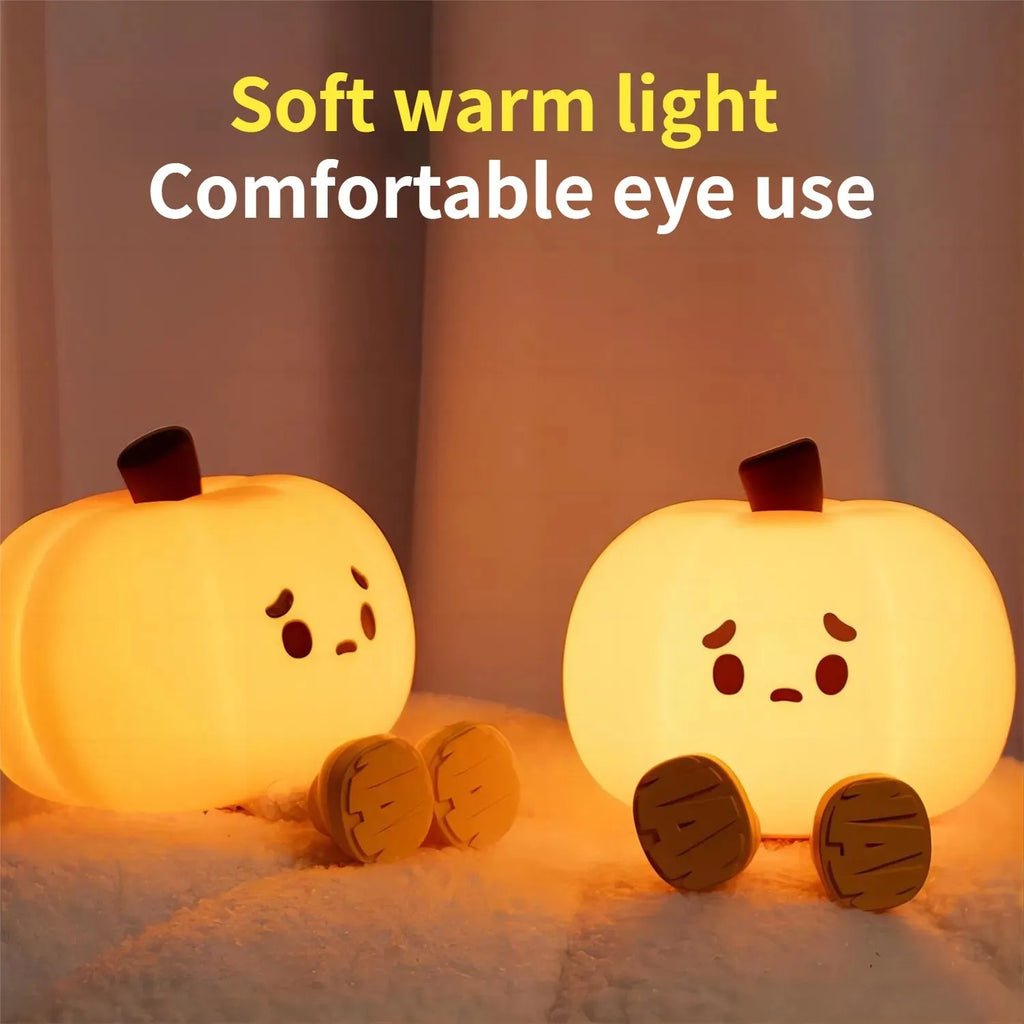 Soft orange pumpkin-shaped silicone night light with a warm glow, showing its compact size on a table.