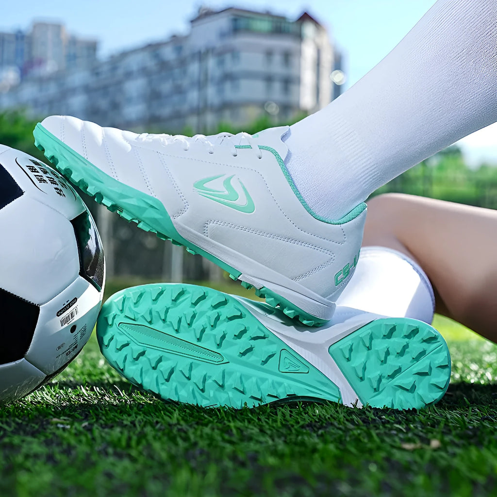 Low-top outdoor soccer shoes in a black and blue broken nails colourway on a turf background.