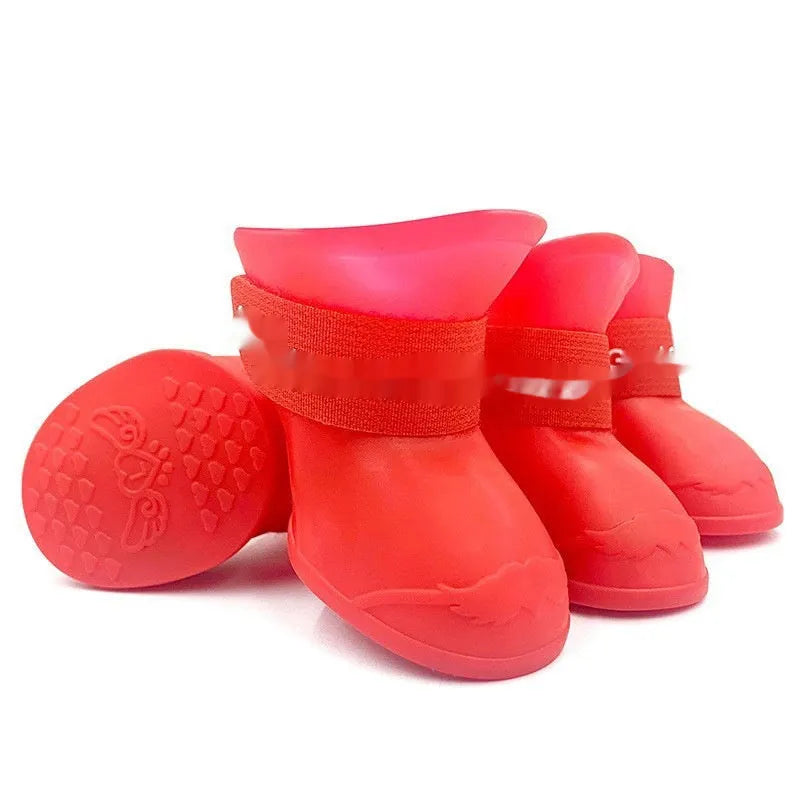 Set of four soft-soled rubber pet rain shoes in assorted colours on a grey background.