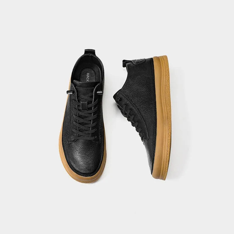 Men's black leather casual shoes with a round toe and white rubber sole on a plain background.