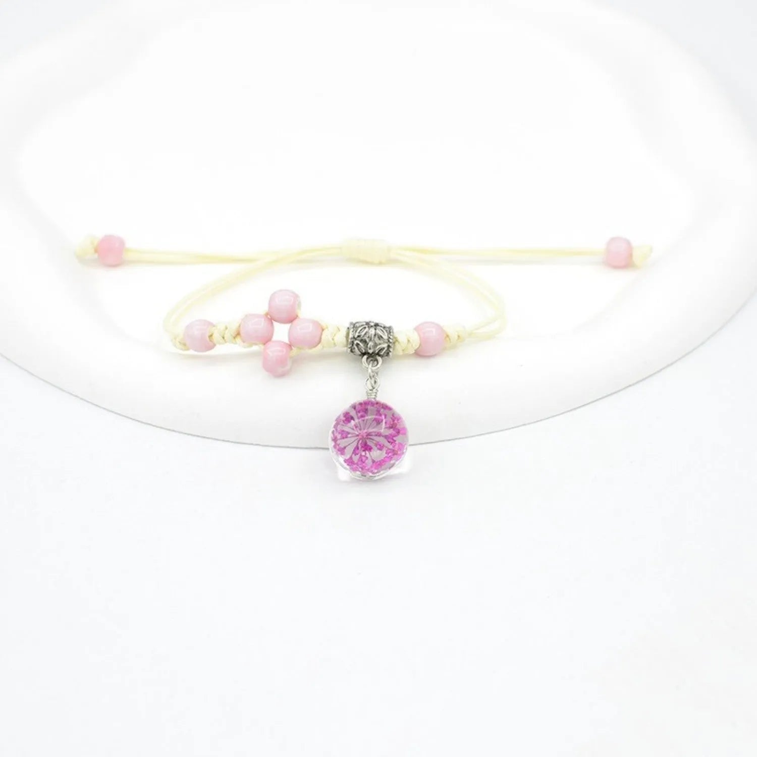 Close-up of a hand-woven glass bracelet with large 1.4cm beads containing real dried flowers in various colours.