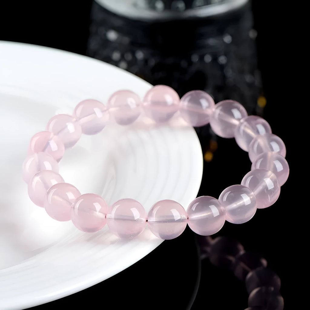 A polished natural starlight crystal round bead bracelet in pink, shown in a single circle design.