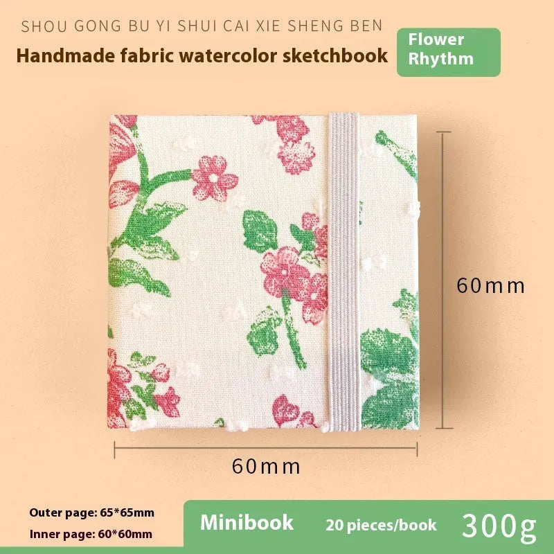Feiluniao handmade fabric watercolour notebook with illustrated cover, open to show blank paper pages.