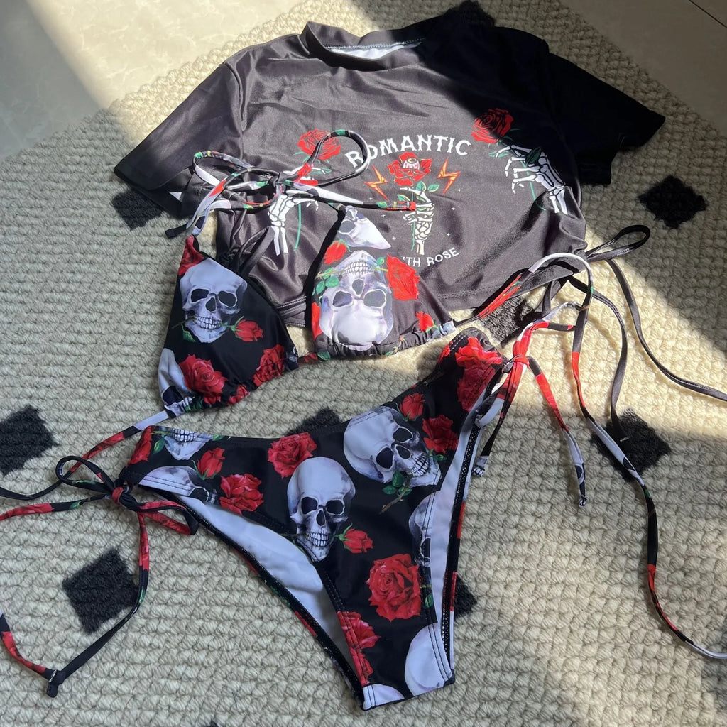 Women's red three-piece swimwear set with skull and rose print showing cropped top, bikini bottoms, and shorts