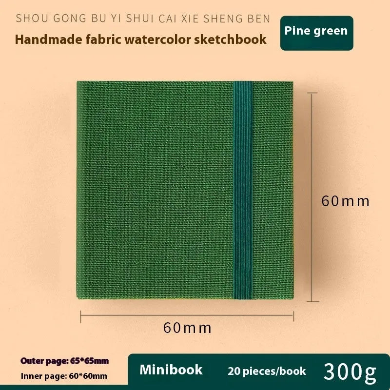 Feiluniao handmade fabric watercolour notebook with illustrated cover, open to show blank paper pages.