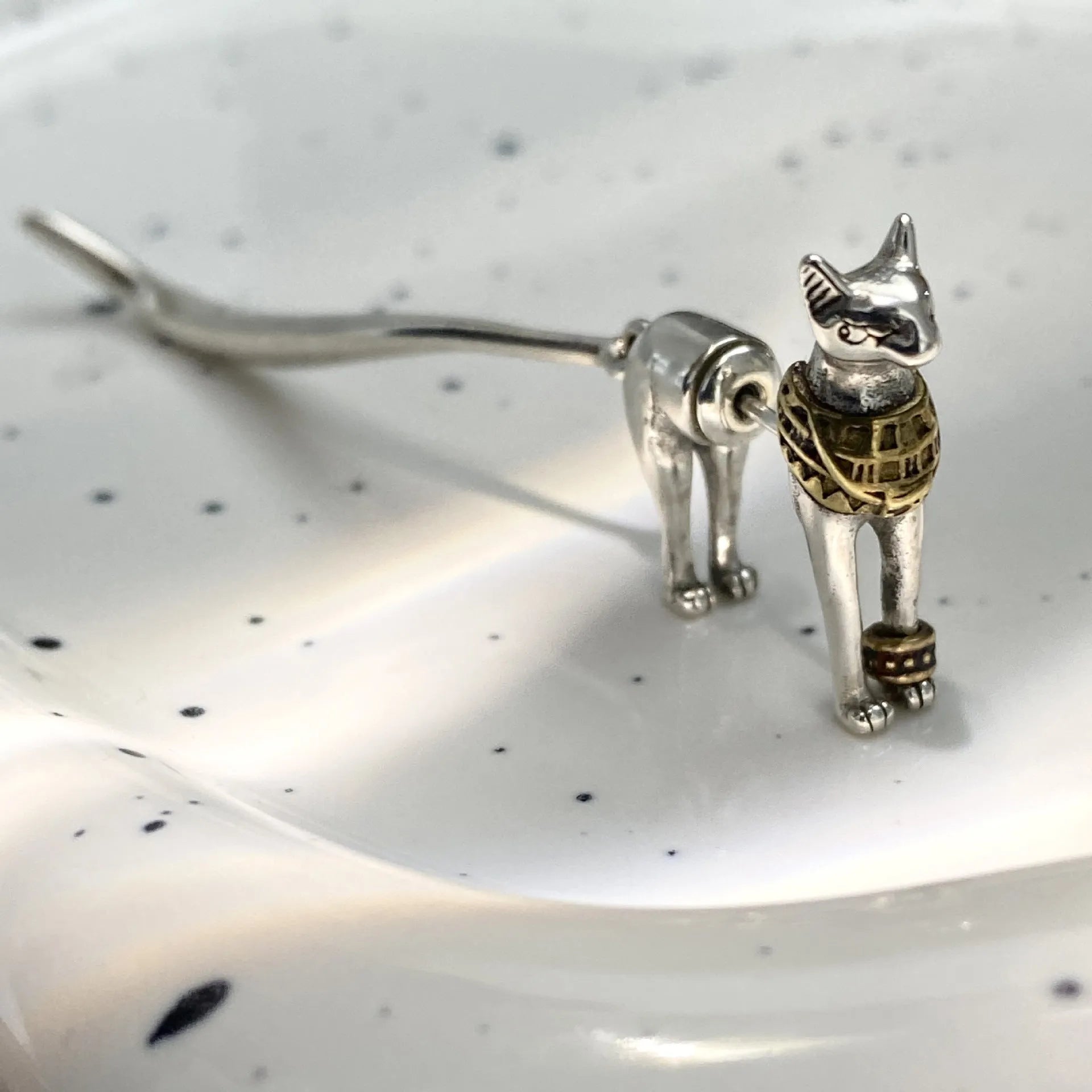 Single copper earring with pharaoh cat shape, gold and silver two-tone copper plated finish, colour separation design