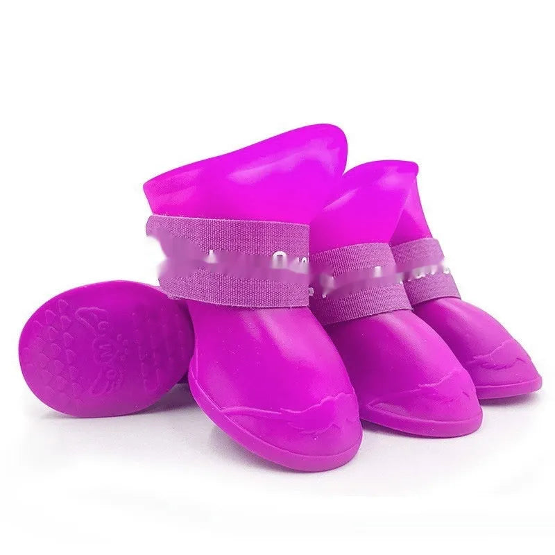 Set of four soft-soled rubber pet rain shoes in assorted colours on a grey background.