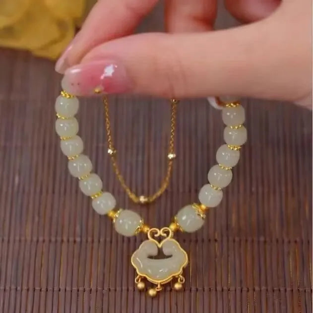 Close-up of a women's green double-layer bracelet with a drop-shaped Xiangyun safety lock pendant.