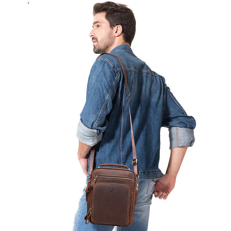 Men's brown genuine leather single-shoulder crossbody bag with visible stitching, shown on a model.