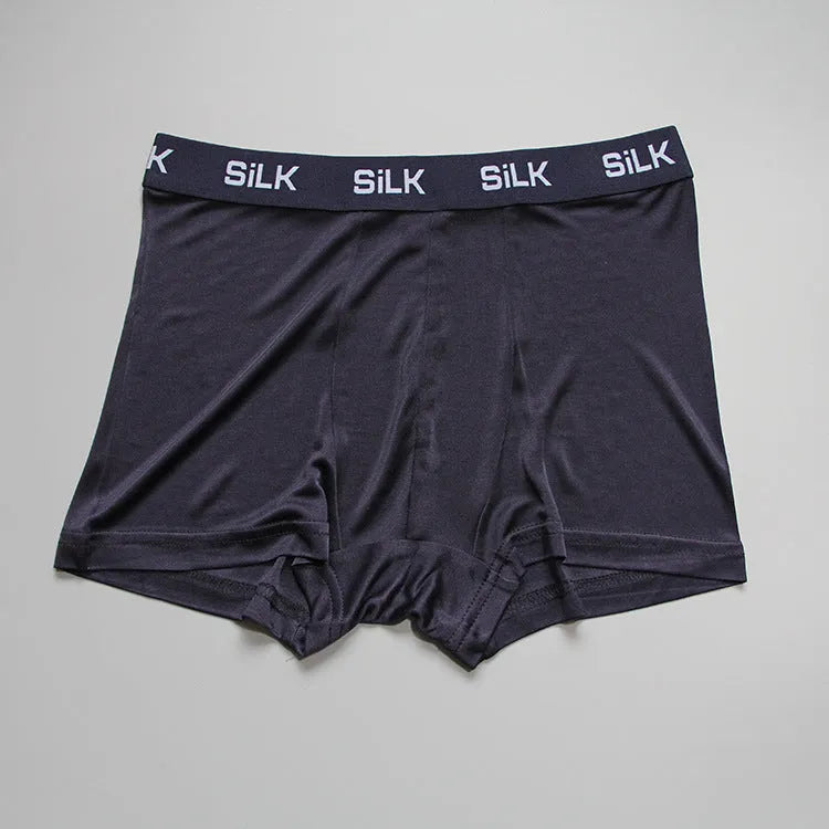 Men's loose-fitting silk shorts in navy blue, shown in a casual setting.