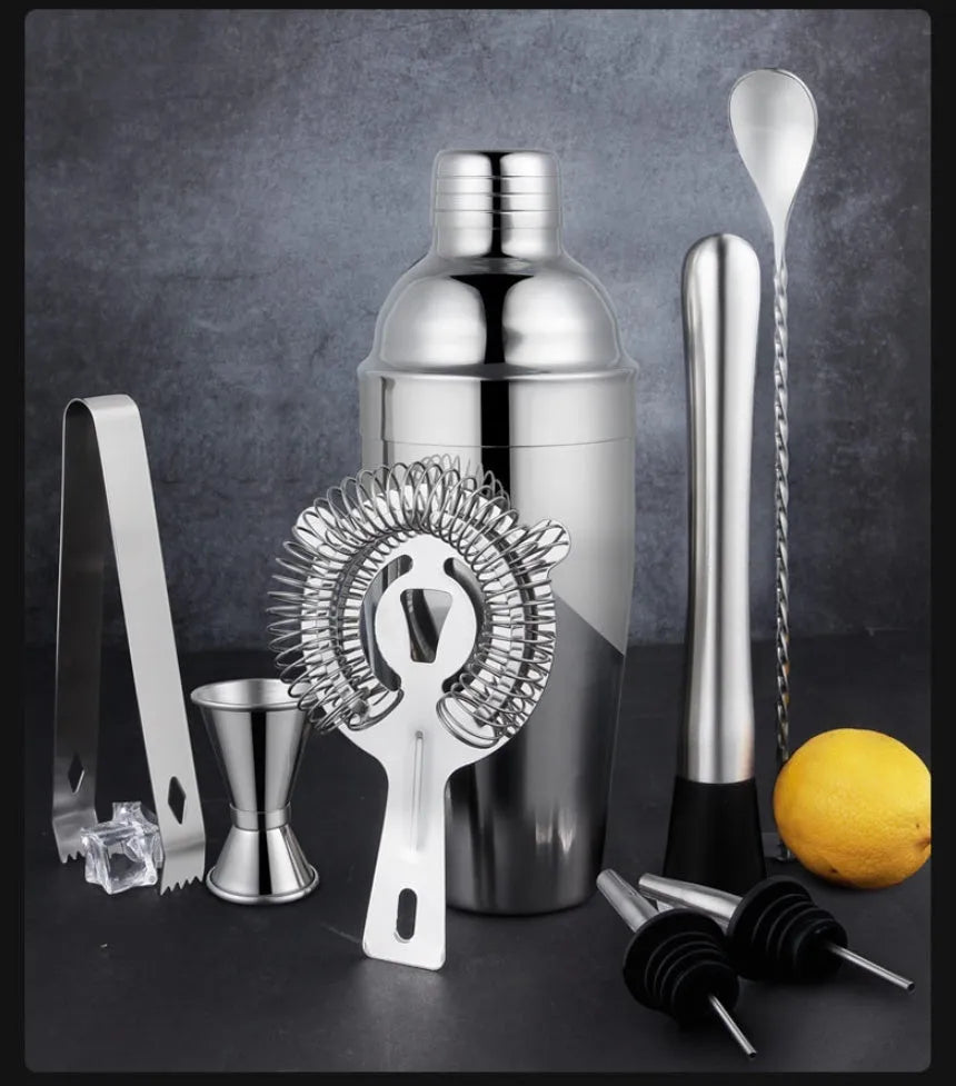 23-piece stainless steel cocktail set with shaker, jiggers, strainer and bar tools on a countertop.