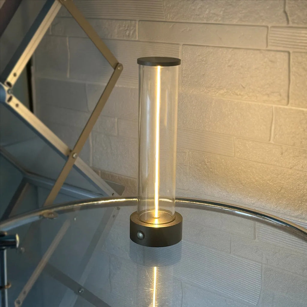Tall cylindrical frosted glass USB rechargeable LED night light with a magnetic base on a wooden surface.