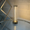 Tall cylindrical frosted glass USB rechargeable LED night light with a magnetic base on a wooden surface.