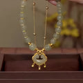 Close-up of a women's green double-layer bracelet with a drop-shaped Xiangyun safety lock pendant.