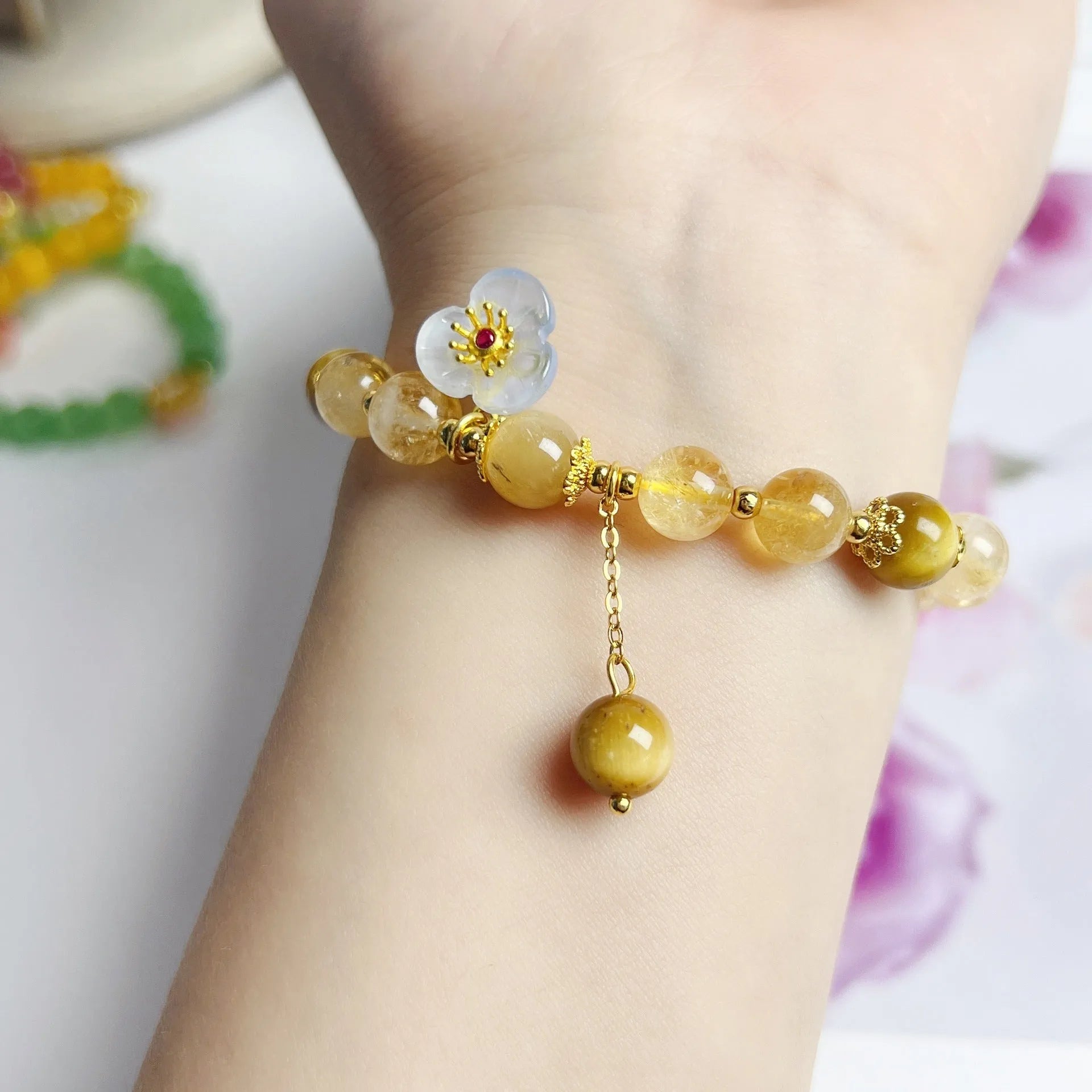 Women's citrine crystal bracelet with gold-plated flower tassel design on wrist.