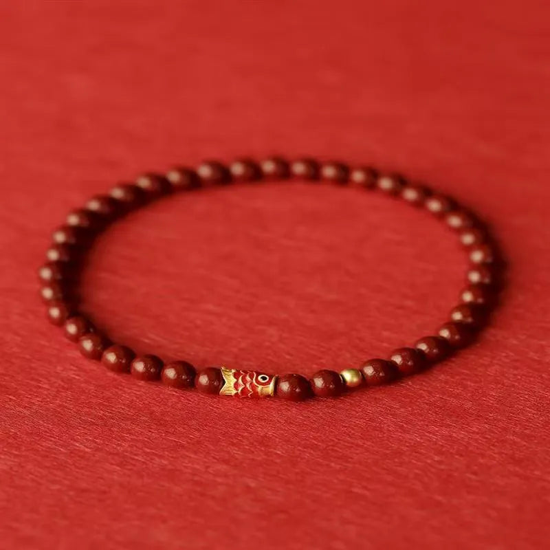 Natural cinnabar koi bracelet with golden ball in national style on a wrist.