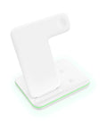 White three-in-one wireless charging stand holding a mobile phone, a smartwatch, and wireless earbuds on a desk.
