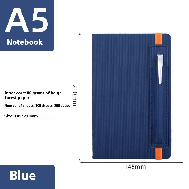 A5 faux leather notebook with pen insert and strap, open on a desk showing lined pages
