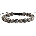 Close-up of a hand-woven flat knot braided bracelet with assorted gemstone beads on a female wrist.