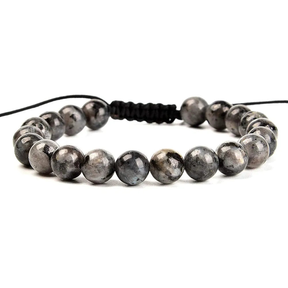 Close-up of a hand-woven flat knot braided bracelet with assorted gemstone beads on a female wrist.