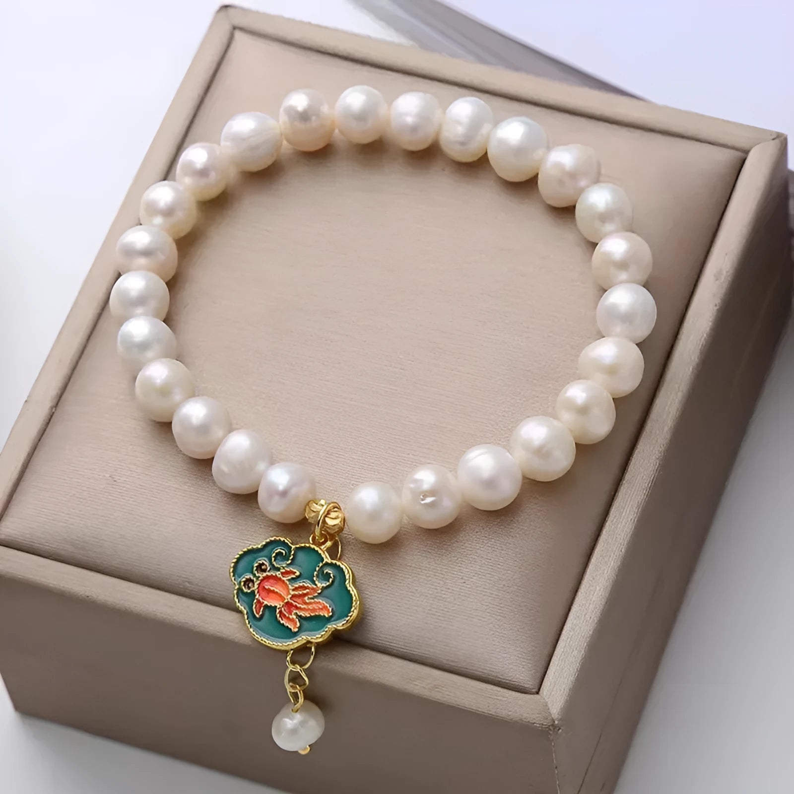 Natural freshwater pearl bracelet with vintage goldfish pendant and lotus motif on white background